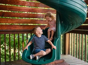 A wooden deck with a green spiral slide. - Ski-Out to Hatley Pointe • Alpine Slide • Rec Room (Mars Hill)