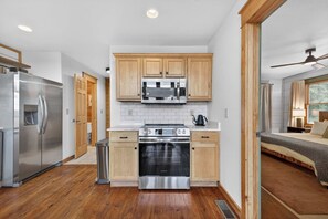 A modern kitchen with wooden cabinets, stainless steel appliances, and a visible trash bin. - Ski-Out to Hatley Pointe • Alpine Slide • Rec Room (Mars Hill)