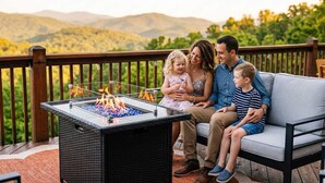 A family on a deck with a glass-top fire feature and a view of hills. - Ski-Out to Hatley Pointe • Alpine Slide • Rec Room (Mars Hill)