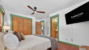 A bedroom with a bed, a ceiling fan, a TV mounted on the wall, and a green-framed door. - Ski-Out to Hatley Pointe • Alpine Slide • Rec Room (Mars Hill)