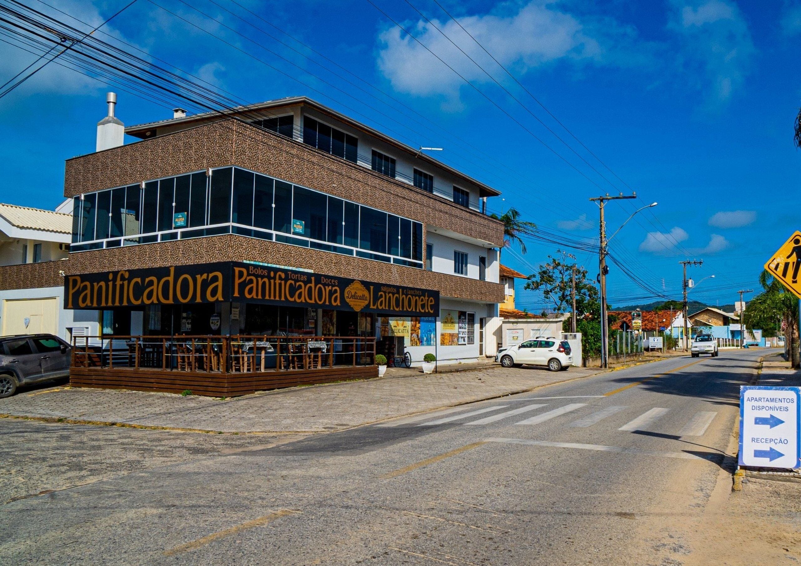 Um edifício de dois andares com um restaurante chamado 'Panificadora Panificadora' no andar térreo.