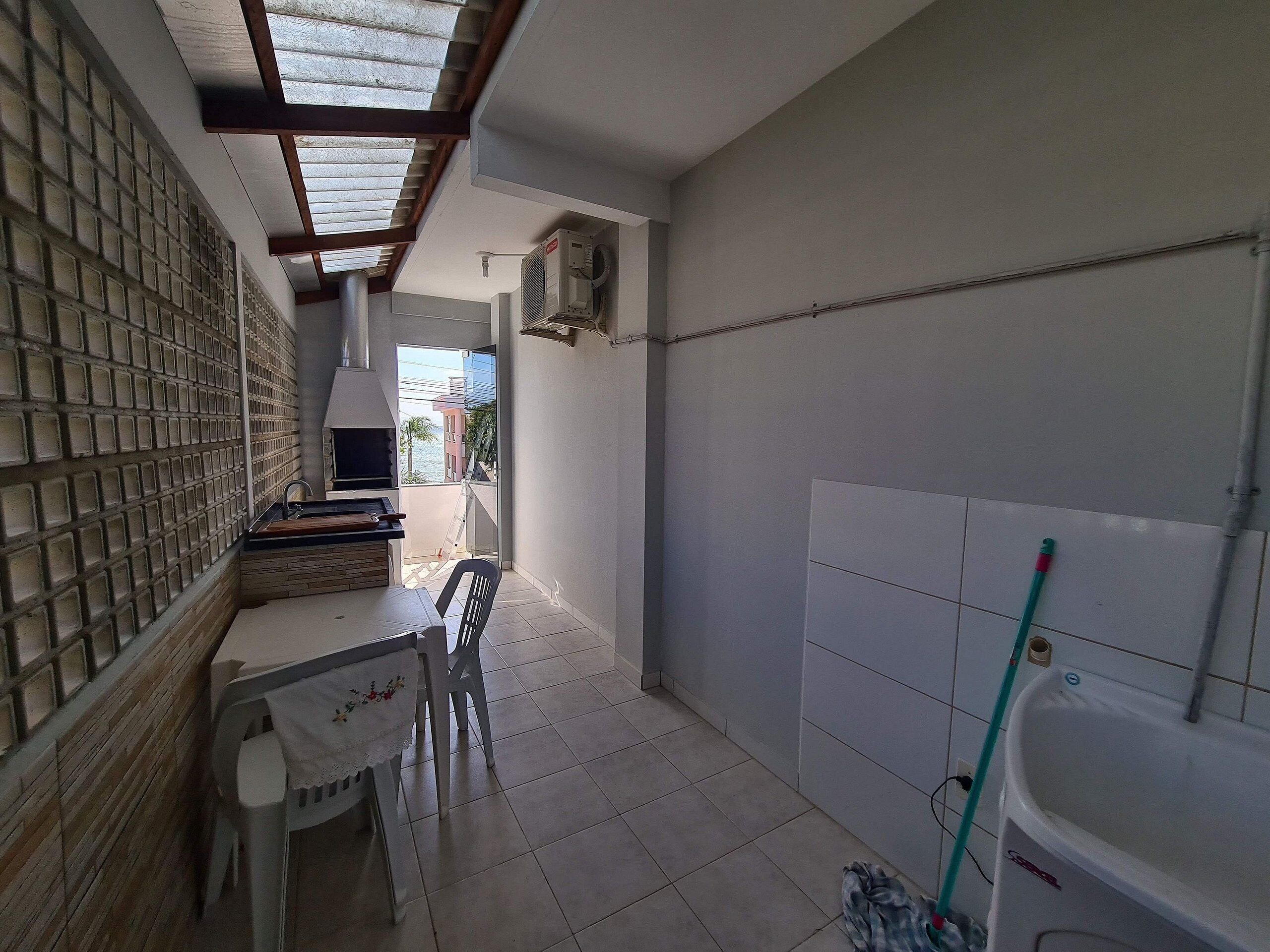 Um quarto pequeno com chão de azulejos, uma mesa com cadeiras, uma janela com vista e um banheiro com banheira e esfregão.