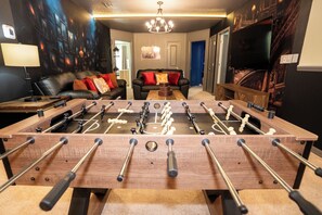 Ein Zimmer mit Kicker, einer Couch und einem Fernseher.