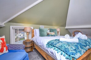 Un dormitorio con cama, mesita de noche, lámpara, ventana con persianas y vista al exterior.