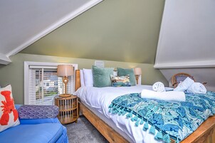 Un dormitorio con cama, mesita de noche, lámpara, ventana con persianas y vista al exterior.