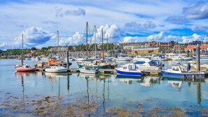 A marina with various boats docked, surrounded by buildings and a clear sky. - Whitby Coastal Cottage (Whitby)