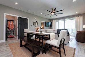 A modern living room with a dark wood dining table, a grey sofa, and a ceiling fan. - Nanna's Nook NEW Heated Indoor Pool Splashpad SDC (Branson)