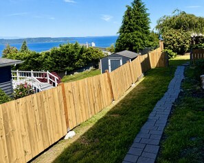 Ein Holzzaun, ein gepflasterter Weg und der Blick aufs Meer.