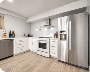 Eine moderne Küche mit Edelstahlgeräten, weißen Schränken und Holzboden.