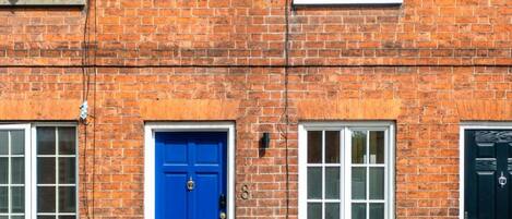 A red brick building with a blue door and white-framed windows.