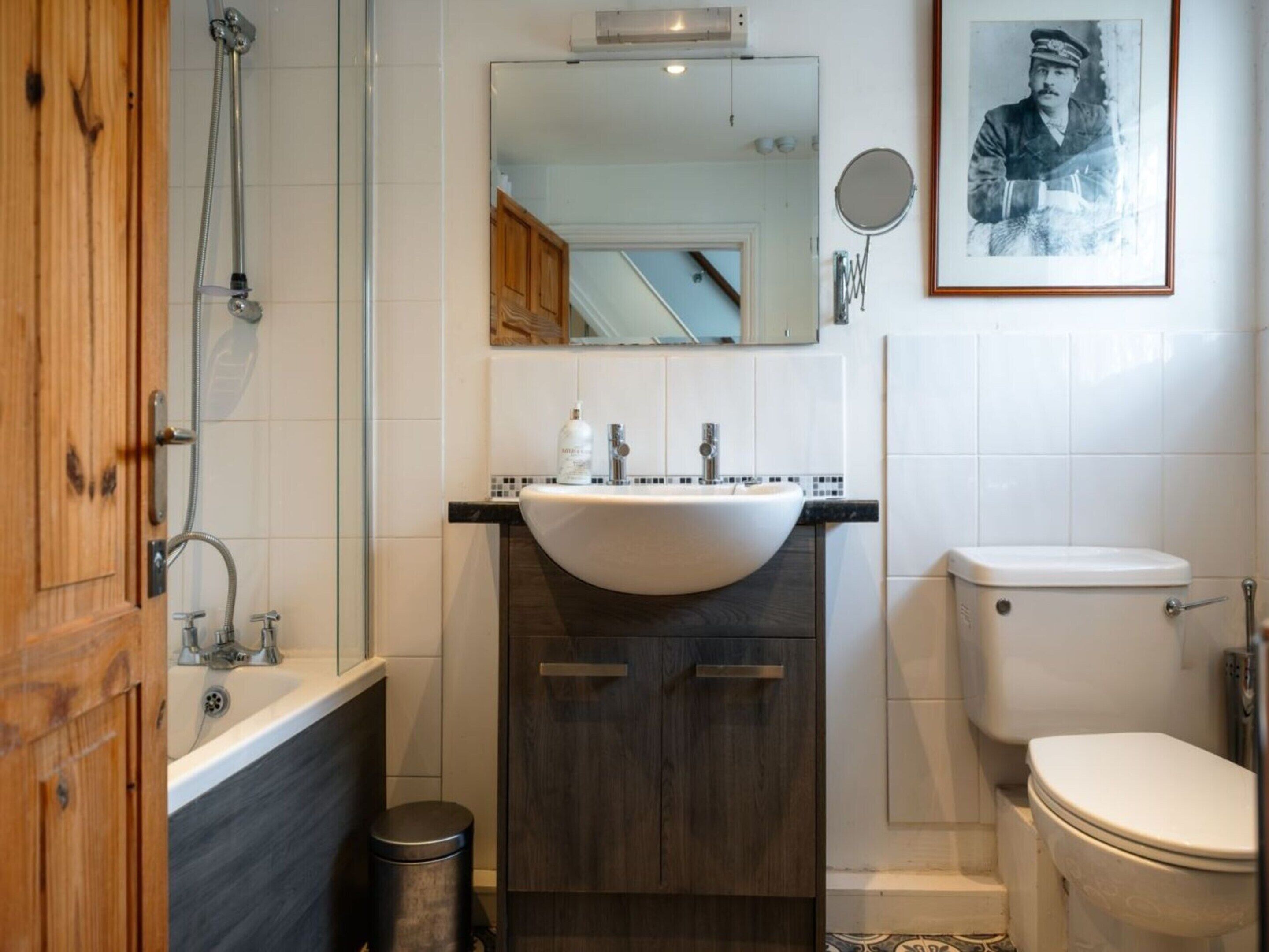 Ein Badezimmer mit Waschtisch aus Holz, einem Waschbecken, einer Toilette und einer Dusche.