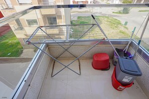 A balcony with a metal drying rack, a red stool, and a grey trash bin. - Cosy Appartement 2 Chambres Avec Balcon à Corniche (Martil)