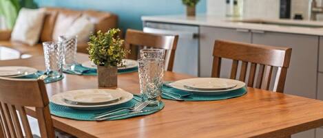 Una mesa de comedor servida con platos, vasos y una pequeña planta.
