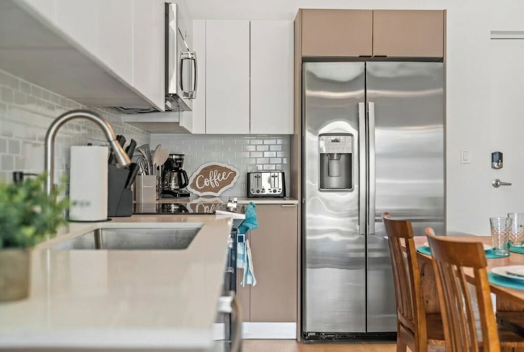 Eine moderne Küche mit einem Edelstahlkühlschrank, einer Kaffeemaschine und einem Toaster.