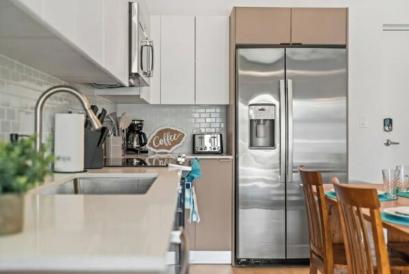 A modern kitchen with a stainless steel refrigerator, a coffee machine, and a toaster.