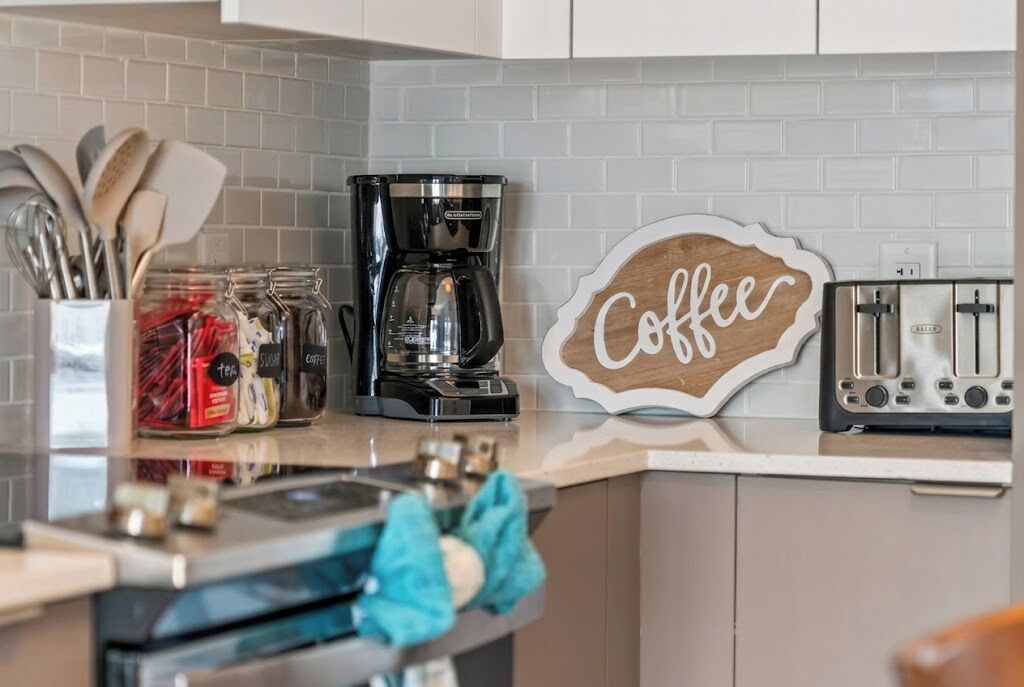 Una cocina con cafetera, tostadora y frascos de azúcar y té.