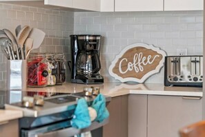 A kitchen with a coffee maker, toaster, and jars of sugar and tea.
