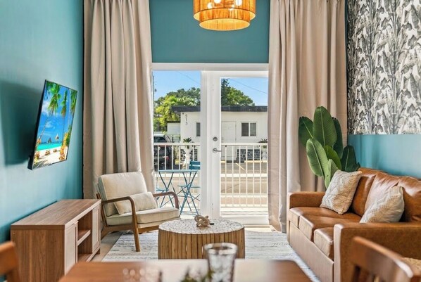 A living room with a sofa, armchair, coffee table, and a view of the outside.