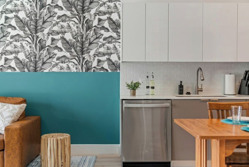 Una cocina moderna con armarios blancos, un lavavajillas de acero inoxidable y un salpicadero de azulejos.