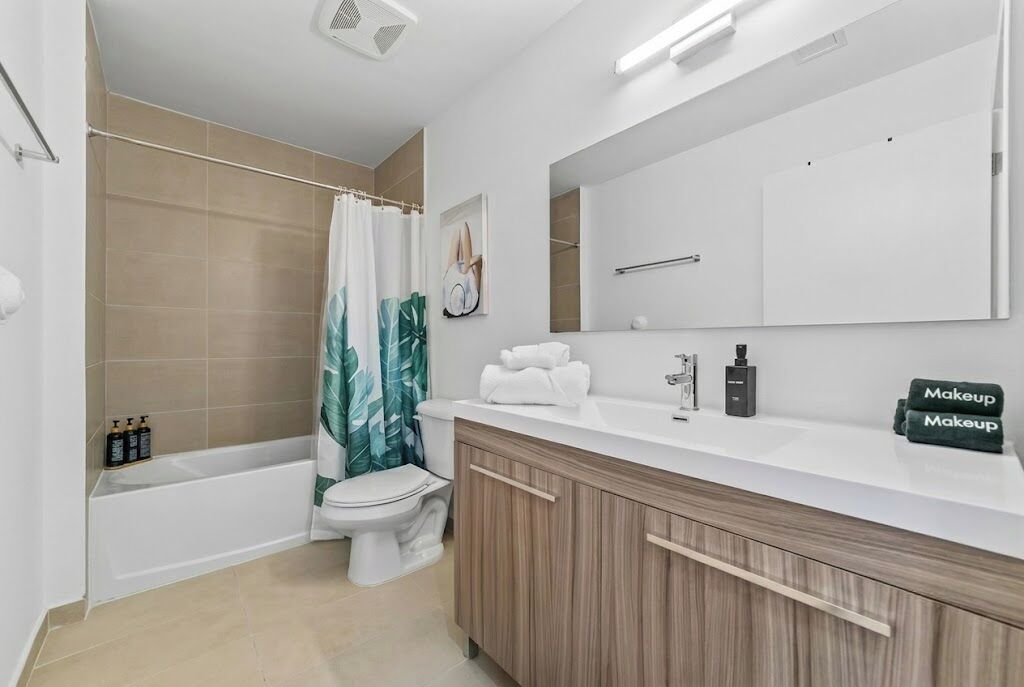 A modern bathroom with a bathtub, toilet, and vanity with a mirror.