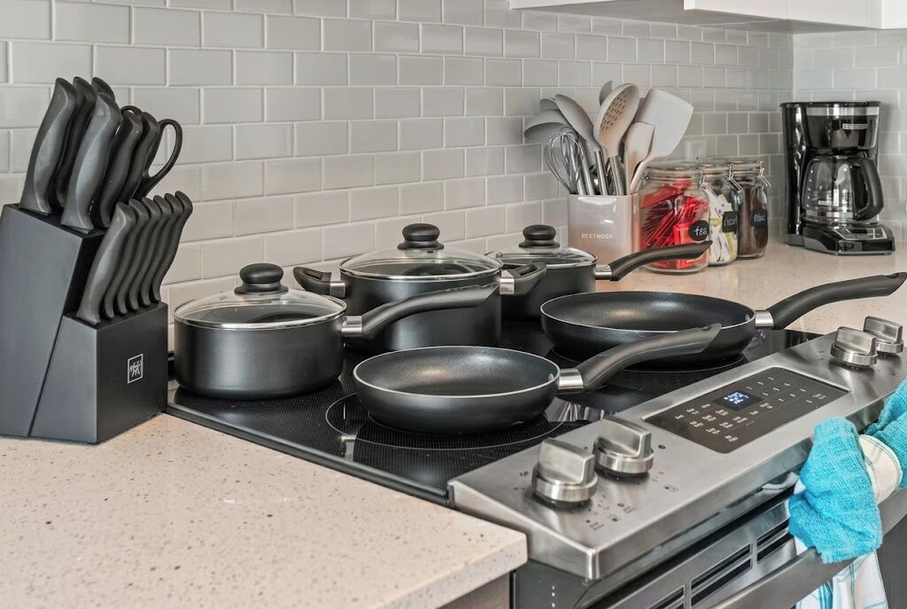 A kitchen with a stove, pots, pans, a knife block, and a coffee maker.