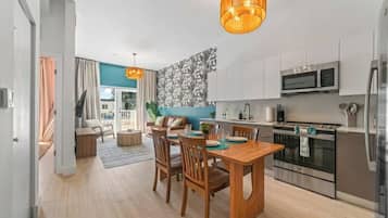 A modern kitchen with stainless steel appliances, a dining area with wooden furniture, and a view to the outside.