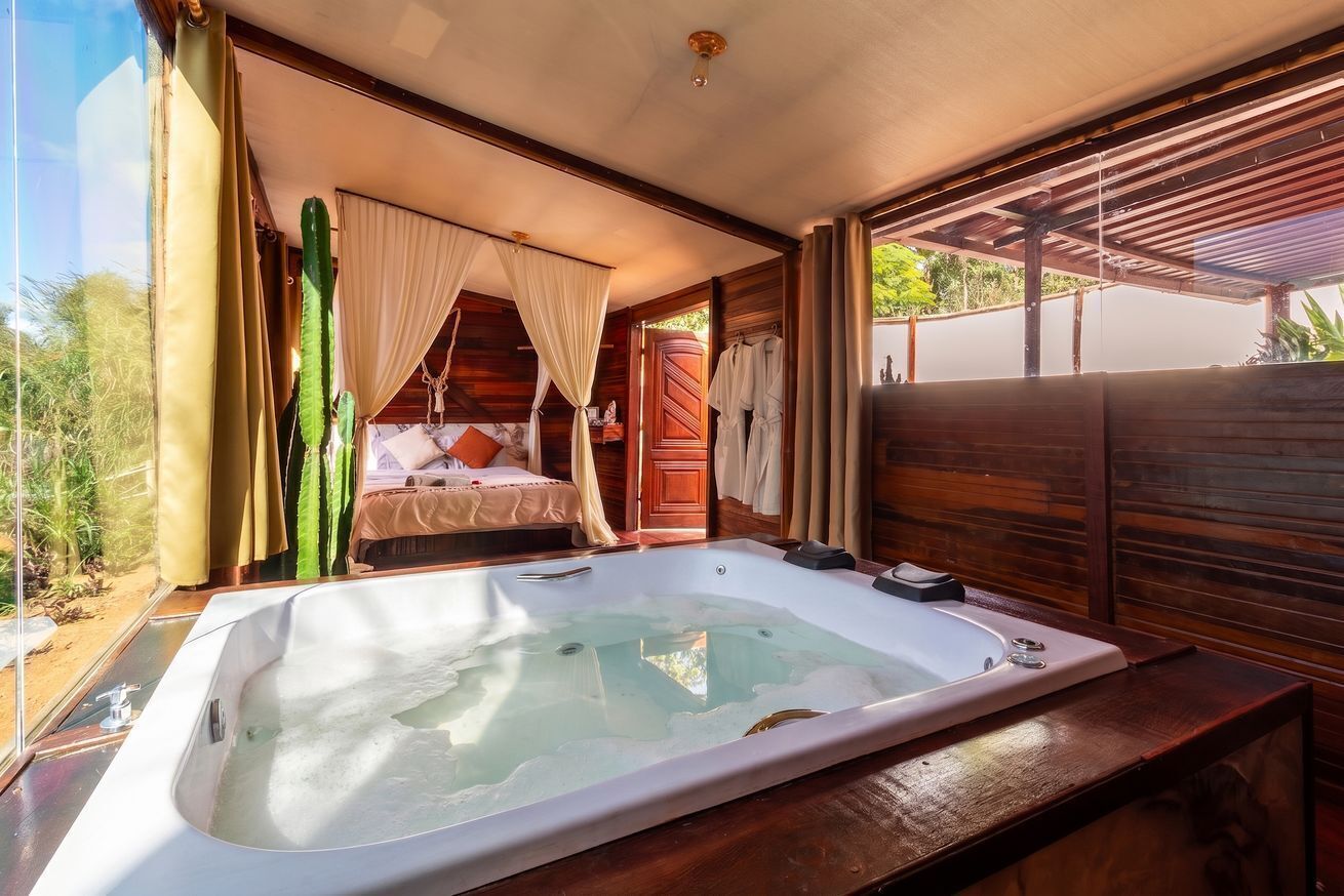 Un dormitorio con una bañera grande, una cama con dosel y vistas al exterior.