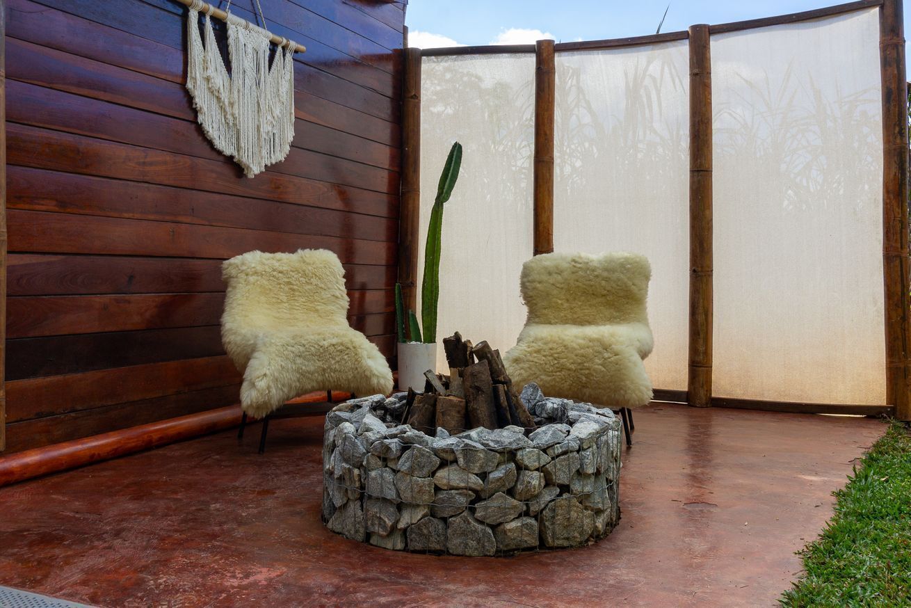 Een terras met twee stoelen, een vuurkorf en een wanddecoratie van macramé.