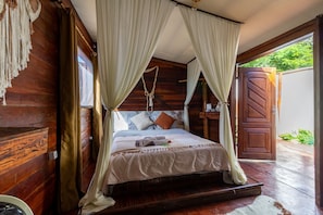 A wooden room with a bed, curtains, and a door leading outside.