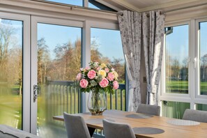 A conservatory with a dining table, chairs, and a vase of flowers.