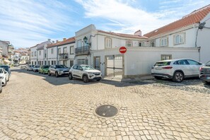 A cobblestone street lined with parked cars and buildings with traditional architecture. - GuestReady - Riverside Retreat (Alcochete)