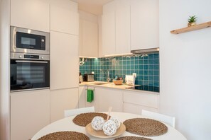 A modern kitchen with white cabinetry, a Bosch microwave, and an oven. - GuestReady - Riverside Retreat (Alcochete)