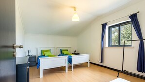 Een kamer met een bed, nachtkastje, lamp en een raam met gordijnen.