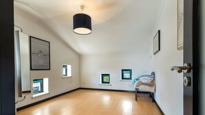 Een kamer met een houten vloer, een plafondlamp, een deur en een raam.