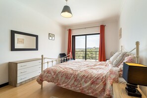 A bedroom with a bed, a desk, a chair, a window with curtains, and a hanging light fixture. - Luxurious Retreat in Lousã Countryside (Lagarteira)