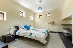 A bedroom with a bed, bedside table, lamp, and a hanging clothes rack. - Luxurious Retreat in Lousã Countryside (Lagarteira)