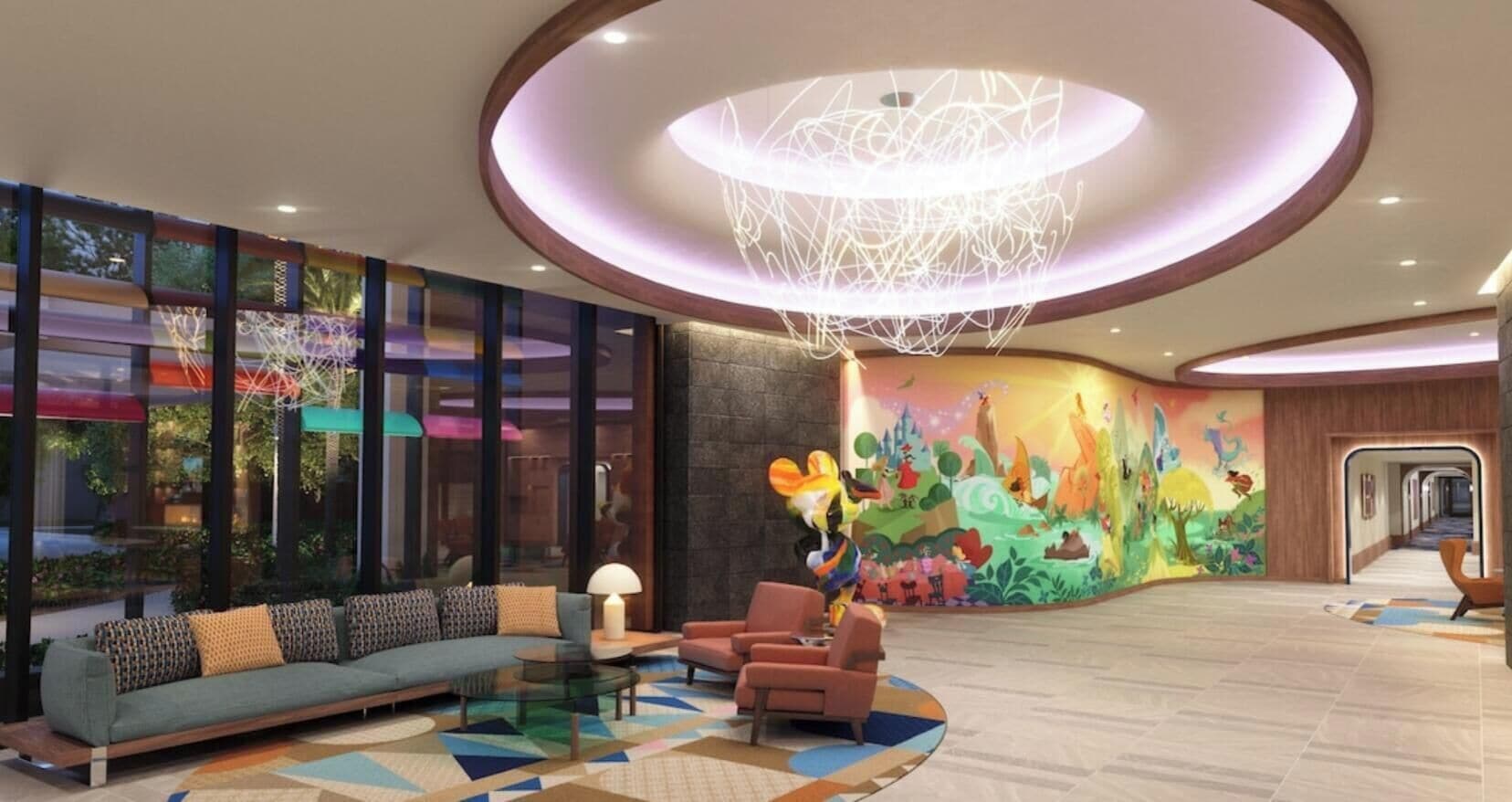 En moderne lobby med et siddeområde med sofaer og lænestole, et farverigt vægmaleri og et unikt pendelarmatur.