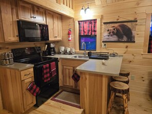 Eine Küchenzeile im Chalet-Stil mit Mikrowelle, Herd, Kaffeemaschine und Spüle.