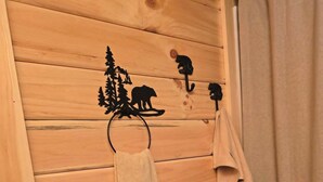 Pared de madeira com porta-toalhas, onde se veem uma toalha e um objeto decorativo.