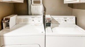 A laundry room with two front-loading washing machines and cabinets above them. - Perfect Downtown Location in Mount Pleasant with AC (Mount Pleasant)