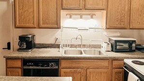 A kitchen with wooden cabinets, a built-in dishwasher, a coffee maker, a sink, a microwave, and a toaster. - Perfect Downtown Location in Mount Pleasant with AC (Mount Pleasant)