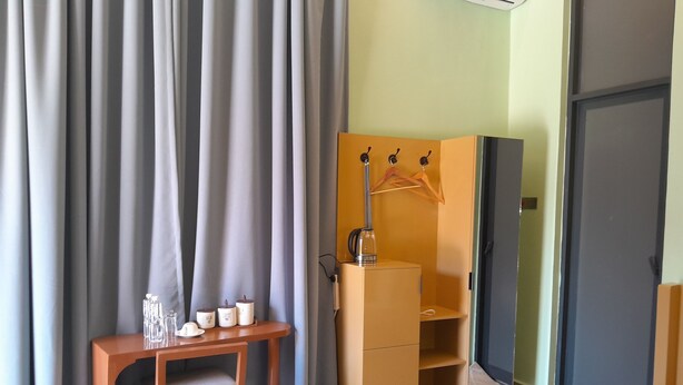 Hotellihuone, jossa on puinen työpöytä, tuoli, vaatekaappi ja sänky.