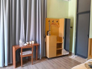 Habitación de hotel con escritorio de madera, una silla, armario y cama.