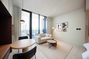 Ein modernes Hotelzimmer mit großem Fenster, einer Couch, einem runden Tisch und einem kleinen Couchtisch.