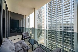Ein Balkon mit einer Couch, einem kleinen Tisch und Blick auf hohe Gebäude.