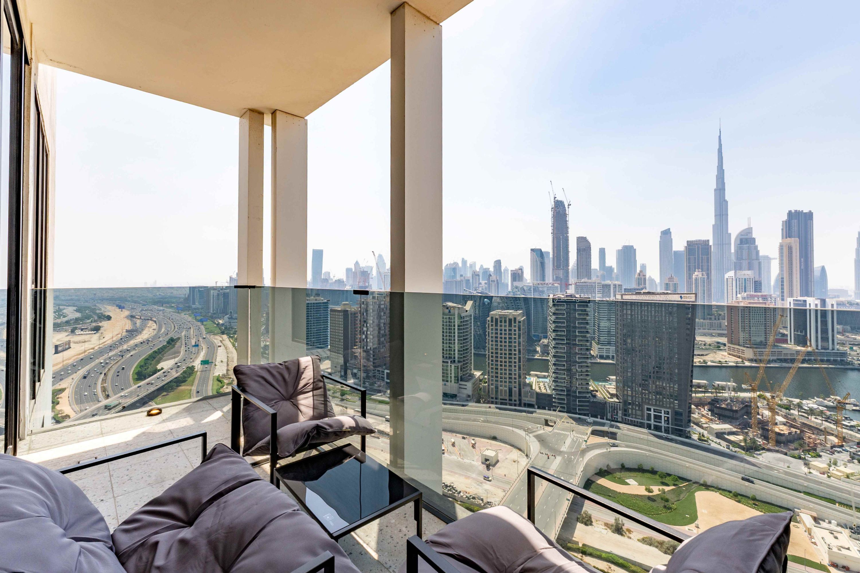 Une chambre située dans un immeuble de grande hauteur, offrant une vue sur la ville, avec une table en verre et un canapé.
