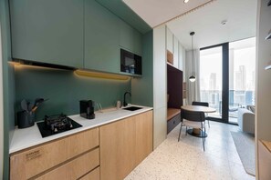 A modern kitchen with a built-in microwave, a coffee maker, and a sink. - Contemporary Studio w/ Burj View (Dubai)