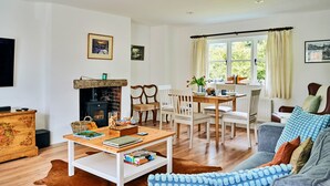 A cozy living room with a fireplace, a dining area, and a sofa. - Historic Cornish Valley Cottage for 5 (Crediton)