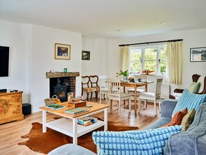 Ein gemütliches Wohnzimmer mit Kamin, Essbereich und einer Couch.