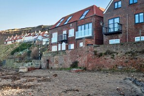 A row of terraced houses with brick facades and white window frames, situated on a hillside. - Seaside Cottage Near Whitby Abbey (Whitby)